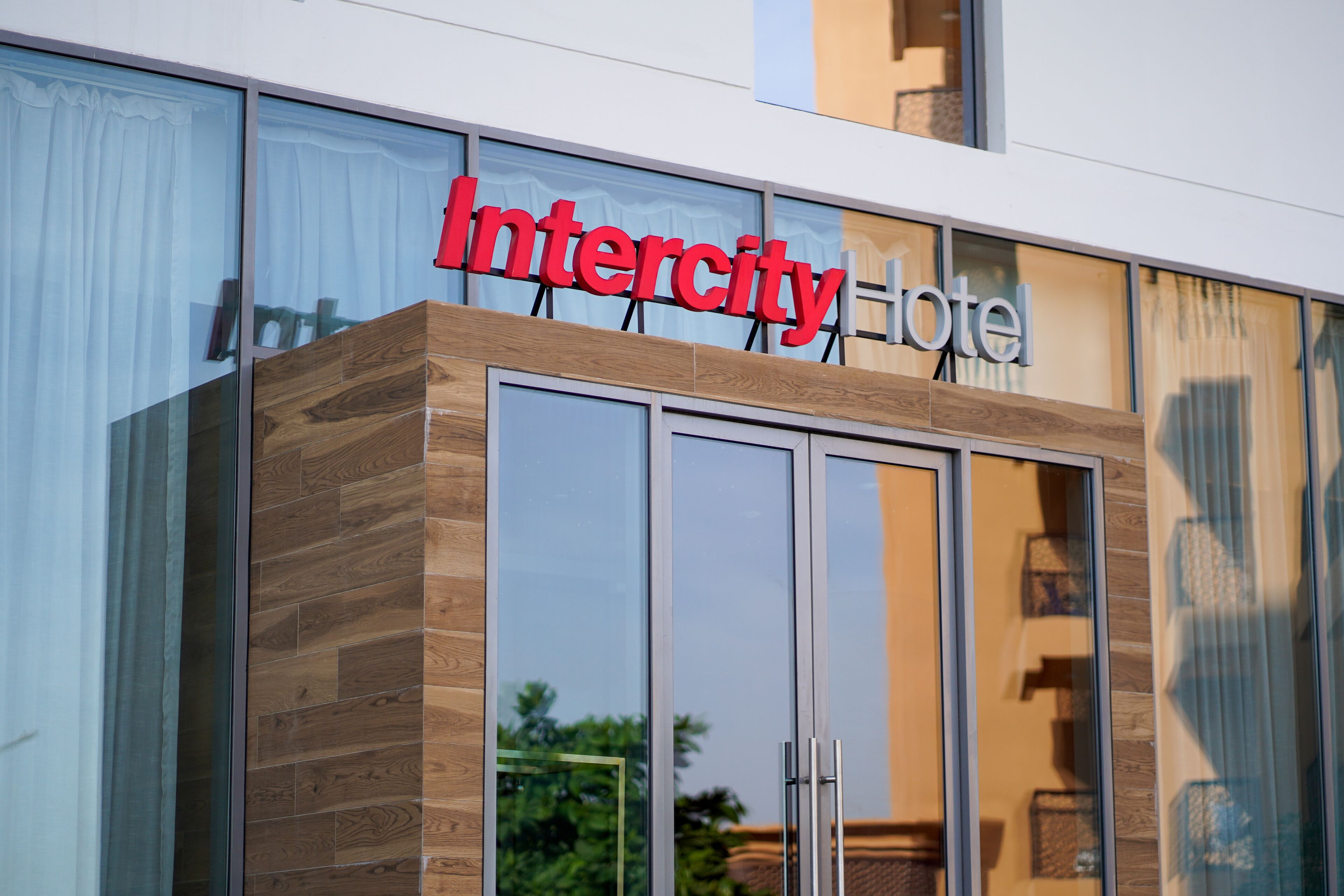 A modern hotel entrance with a large sign reading "Intercity Hotel" above a glass door.