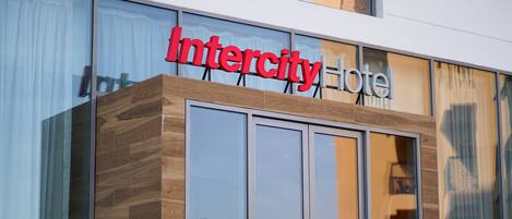 A modern hotel entrance with a large sign reading "Intercity Hotel" above a glass door.