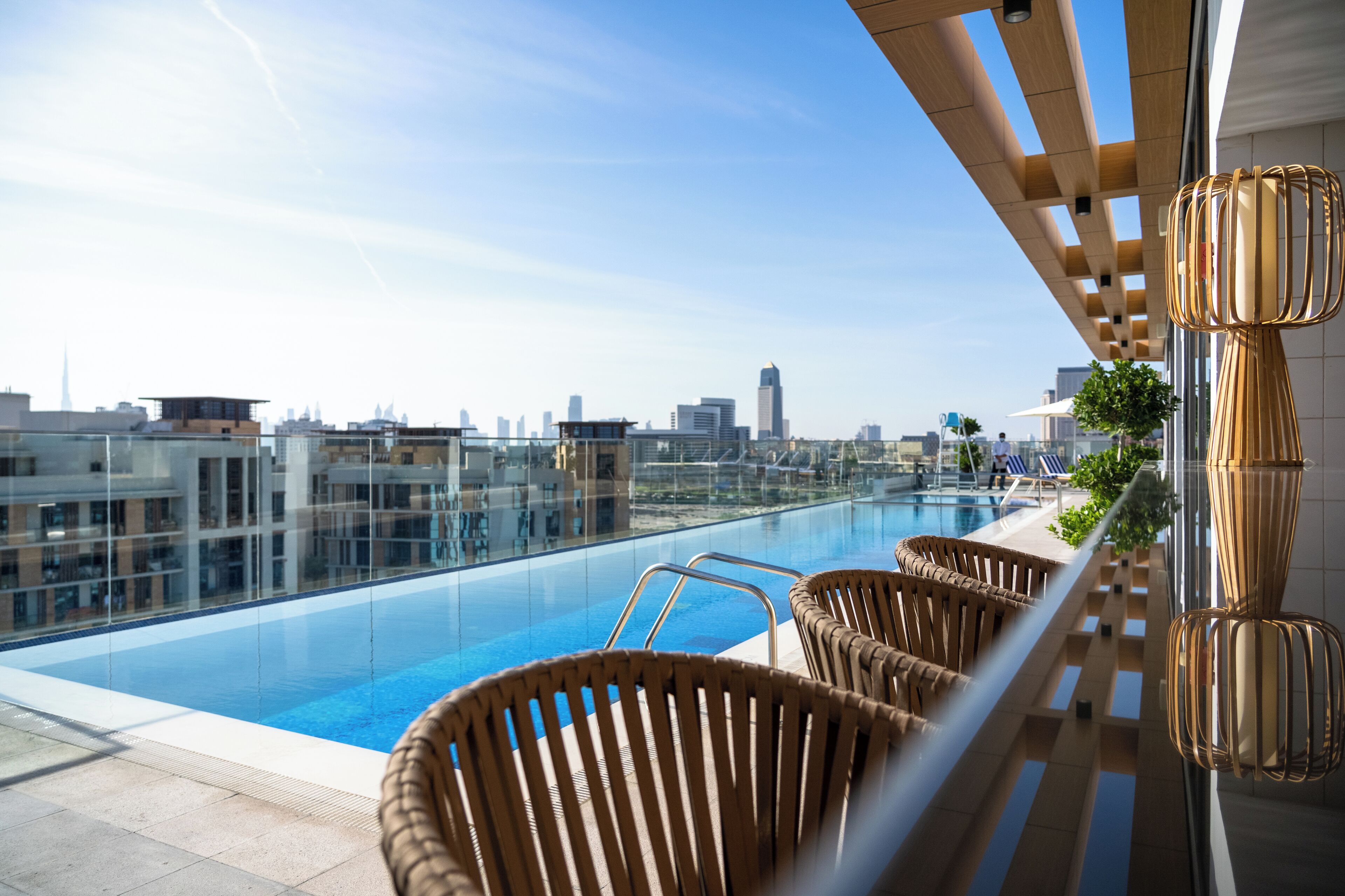A rooftop pool with wicker chairs and a city view.