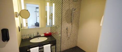 A modern bathroom with a glass-enclosed shower, a black vanity with a sink, and a large mirror.