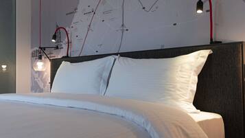 Una cama bien hecha con sábanas blancas, cabecera con panel oscuro y mapa de pared con una línea roja.