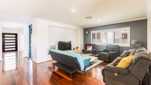 A living room with a sofa, two armchairs, a coffee table, and a TV. - Quay River Beach Hotel (Biggera Waters)