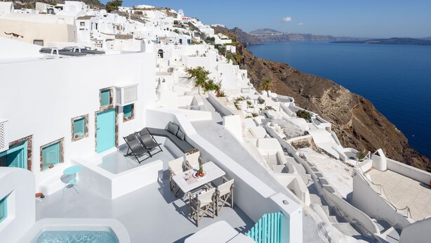 A white-washed building with a pool, outdoor seating, and a view of the sea. - Cave Agapi house with private hot tub and view of the Oia caldera (Oia)