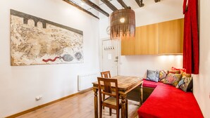 Une pièce comprenant une table à manger en bois, des chaises, un canapé rouge, un grand tableau abstrait et un buffet en bois.