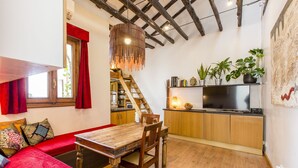 Une cuisine compacte avec des meubles en bois, un coin repas avec une table et des chaises en bois, et un escalier menant à un niveau supérieur.