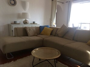 A living room with a beige sectional sofa, a small round table, a white cabinet, and a decorative plate on the wall. - Villa Casa Monte, Quinta Do Paraiso, Carvoeiro Fibre WiFi (Carvoeiro)