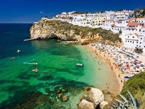 Une ville côtière dotée d’une plage, d’eaux cristallines et de bâtiments blancs.