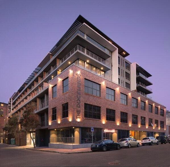 A multi-story building with a brick facade, balconies, and a ground-level storefront. - Urban Elephant At The Docklands (Cape Town)