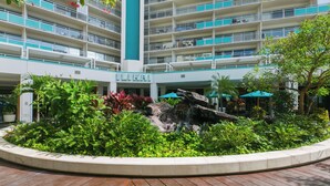 A multi-story hotel with a central atrium, outdoor seating area, and lush landscaping. - Ilikai Hotel 1 Bedroom Yacht Harbor View, minutes to the Beach! (Honolulu)