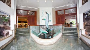 A lobby with a central fountain, a staircase, and a reception area. - Ilikai Hotel 1 Bedroom Yacht Harbor View, minutes to the Beach! (Honolulu)