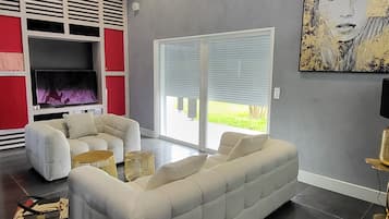 Un salon moderne avec un canapé d’angle, un téléviseur à écran plat, une grande fenêtre et une bibliothèque intégrée aux couleurs rouge et blanche.