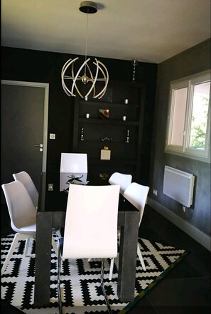 A modern dining area with a white table and chairs, a black and white patterned rug, and a pendant light.