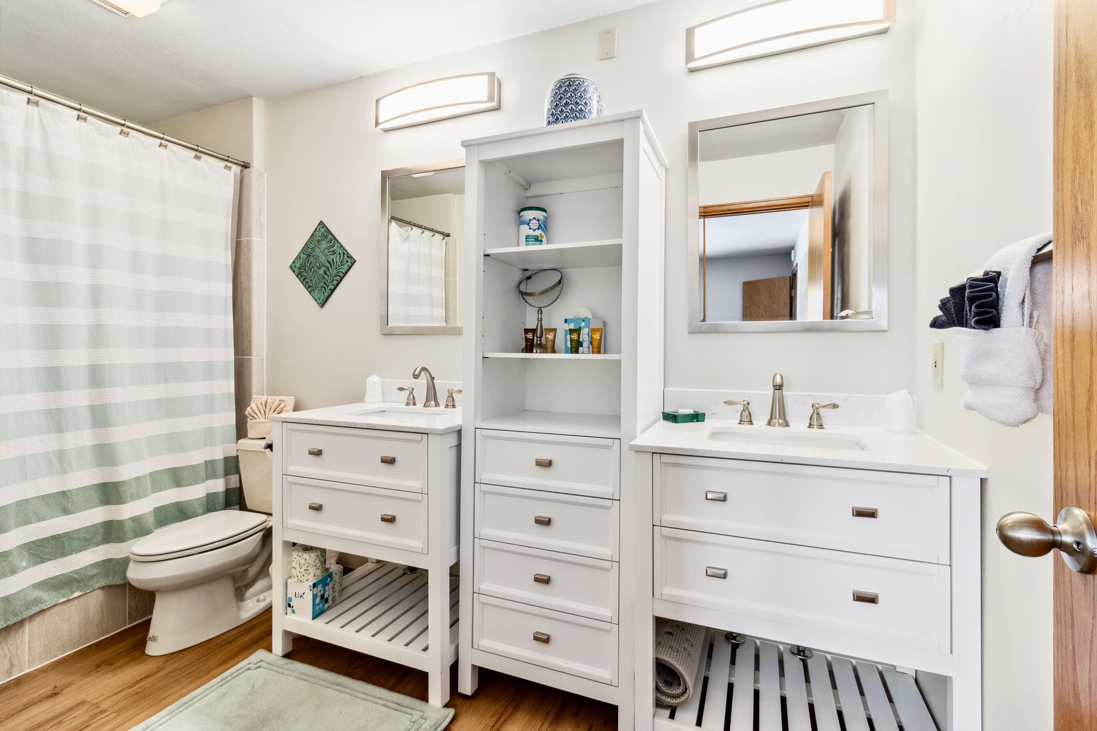 A bathroom with two sinks, a toilet, and a shower curtain.