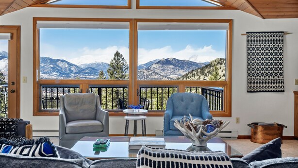 A cozy living room with large windows offering a mountain view, a fireplace, and a comfortable seating area.