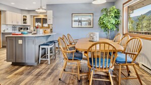 A modern kitchen with a central island, wooden chairs, and a dining table.
