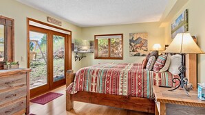 A bedroom with a wooden bed, a nightstand, a desk, and a large window. - Divine Destiny Luxury At Windcliff 6 Bedroom Condo by RedAwning (Estes Park)