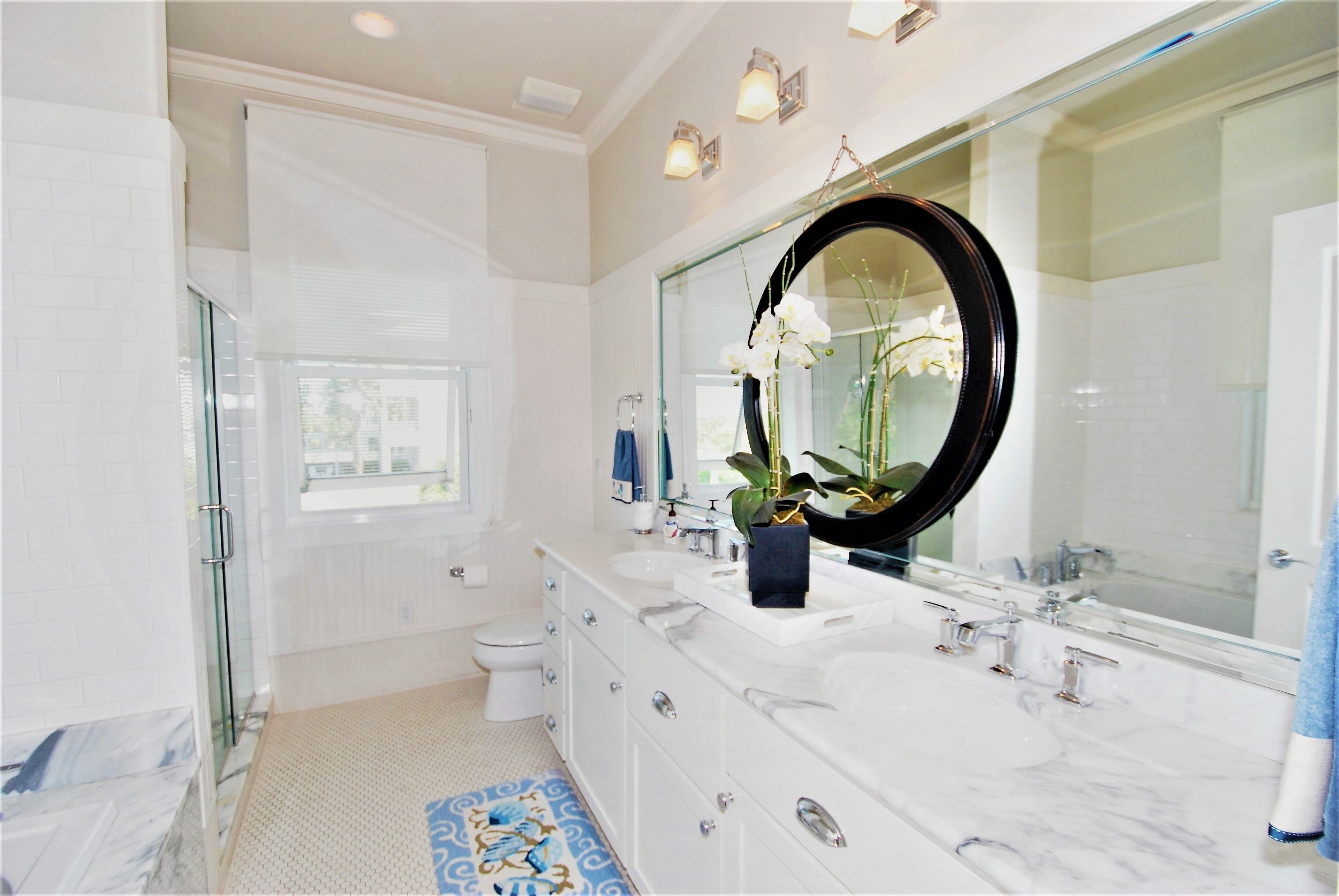 A modern bathroom with a large mirror, white vanity, and a glass shower enclosure.