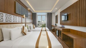 A hotel room with a large bed, a desk, a TV, and a view of the city. - Prague Hotel (Da Nang)