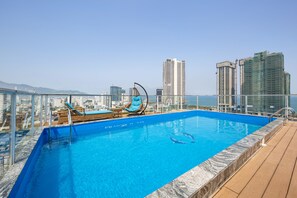 Ein Rooftop-Pool mit Infinity-Kante, Liegestühlen und Blick auf die Stadt.