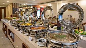 A buffet with various dishes and a Coca-Cola refrigerator in the background. - Prague Hotel (Da Nang)