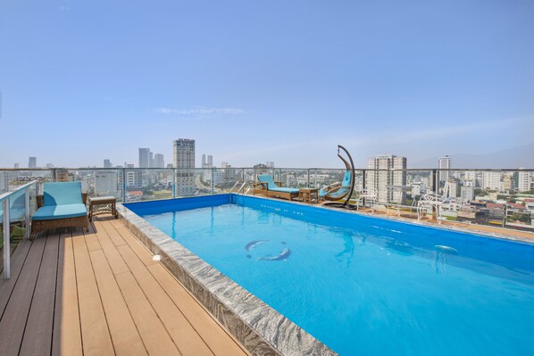 Ein Pool auf dem Dach mit Liegestühlen und Blick auf die Stadt.