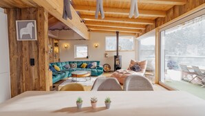 A modern interior with wooden beams, a sofa, a bed, and a view through large windows. - Das Mountain Getaway - 'Upper Two Floors' (Fulpmes)