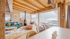 A cozy wooden interior with a large dining table, a sofa, and a fireplace. - Das Mountain Getaway - 'Upper Two Floors' (Fulpmes)
