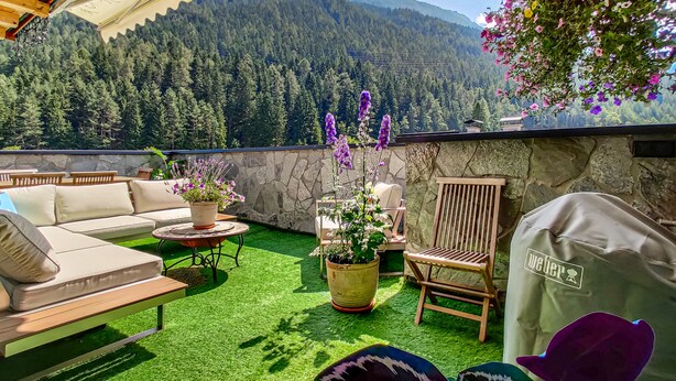 A patio with a sofa, chairs, and a grill area, overlooking a forested mountain. - Das Mountain Getaway - 'Upper Two Floors' (Fulpmes)