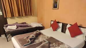 A hotel room with a bed, a smaller bed or sofa, and a wall-mounted shelf. - Hotel Trio Tourist (New Delhi)