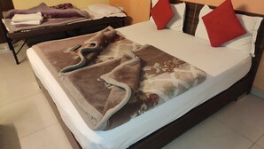 A hotel room with a bed, a bedside table, and a chair. - Hotel Trio Tourist (New Delhi)
