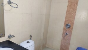 A bathroom with a toilet, sink, and shower area. - Hotel Trio Tourist (New Delhi)