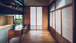 A traditional Japanese room with tatami flooring, sliding doors, and a low wooden table with a black object on it.