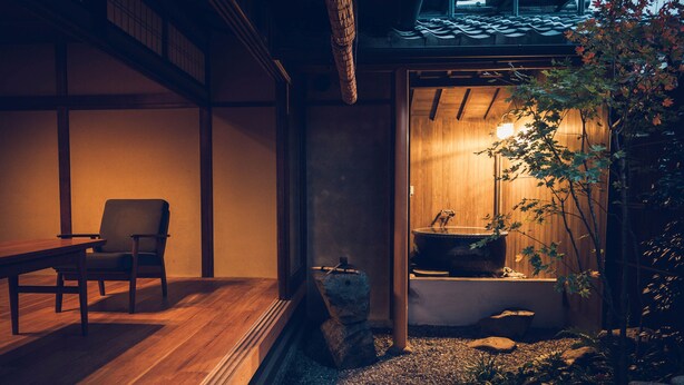 A traditional Japanese-style room with tatami flooring, a low wooden table, and a seating area.