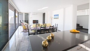 Uma área de refeições moderna com divisória de vidro, uma TV de tela plana e uma mesa de jantar com cadeiras.