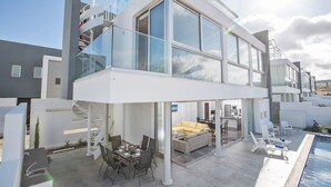 Uma casa moderna de dois andares com varanda, área de estar ao ar livre e piscina.