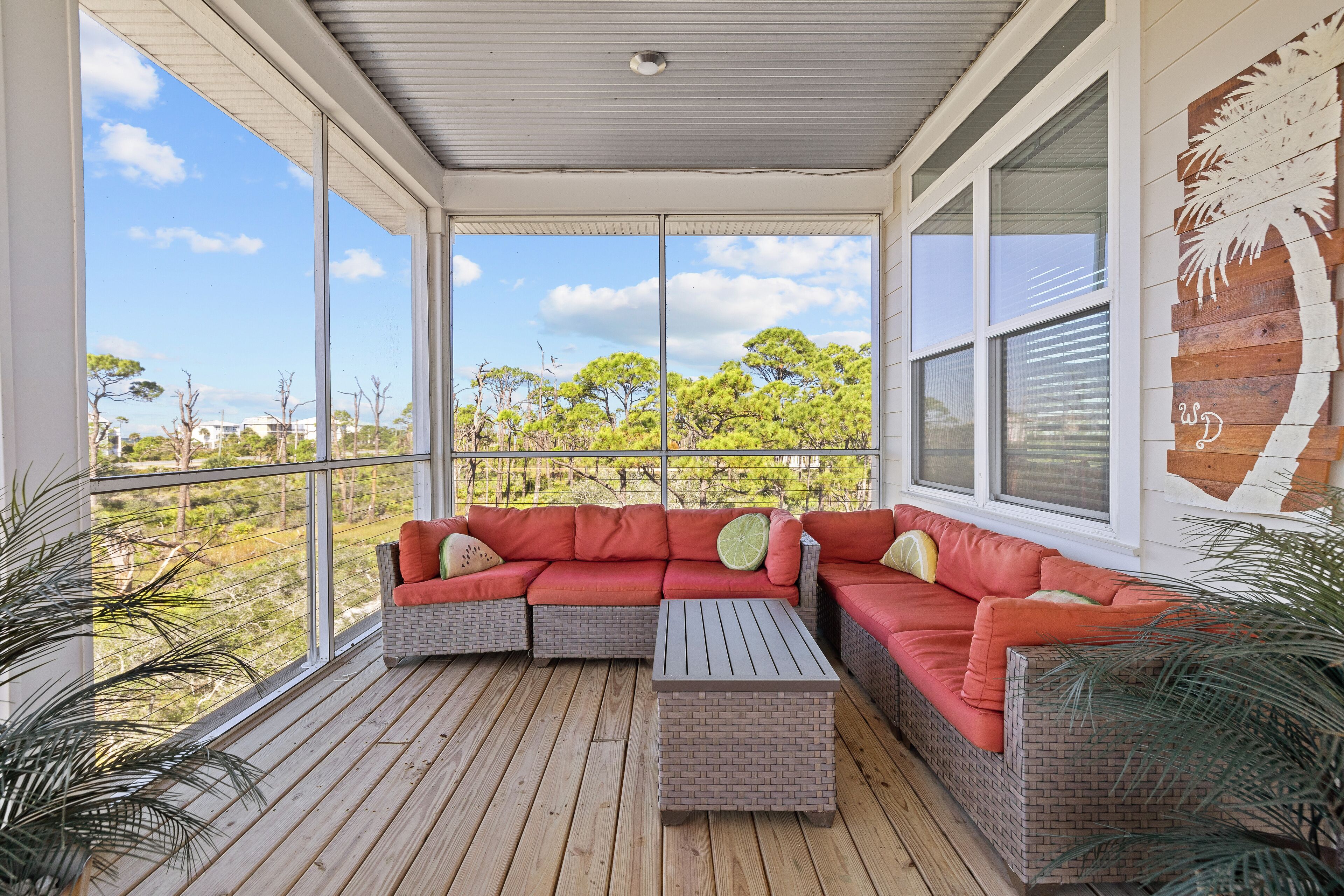 A covered outdoor seating area with wicker furniture and a view of trees and buildings.