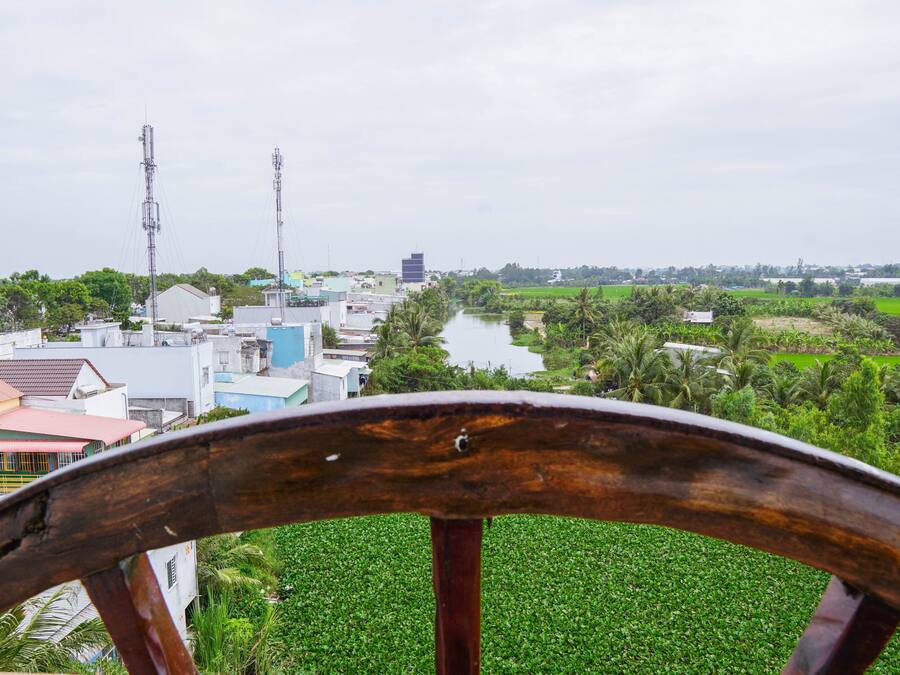 A view from a wooden structure overlooking a town with buildings, a river, and green fields.