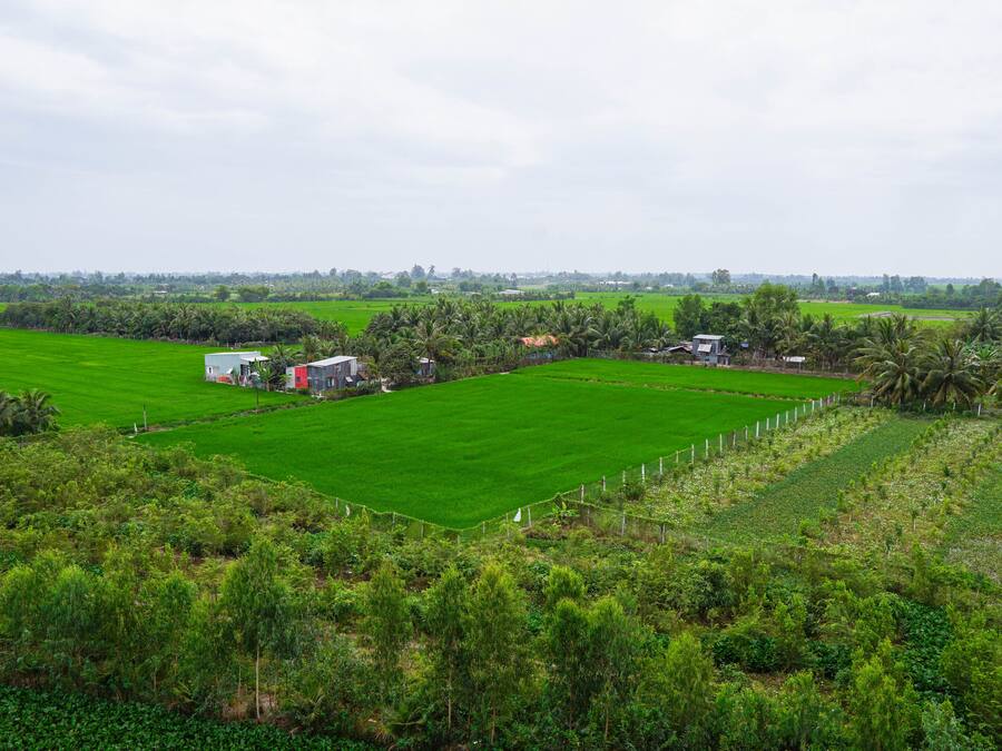 A rural landscape with green fields, a few buildings, and a fence.