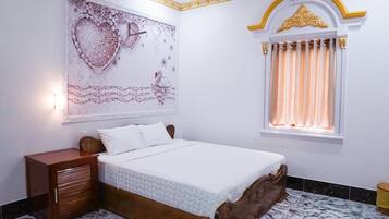 Camera da letto con un letto, un comodino, un elemento decorativo a parete, una finestra con tende e un pavimento in marmo.