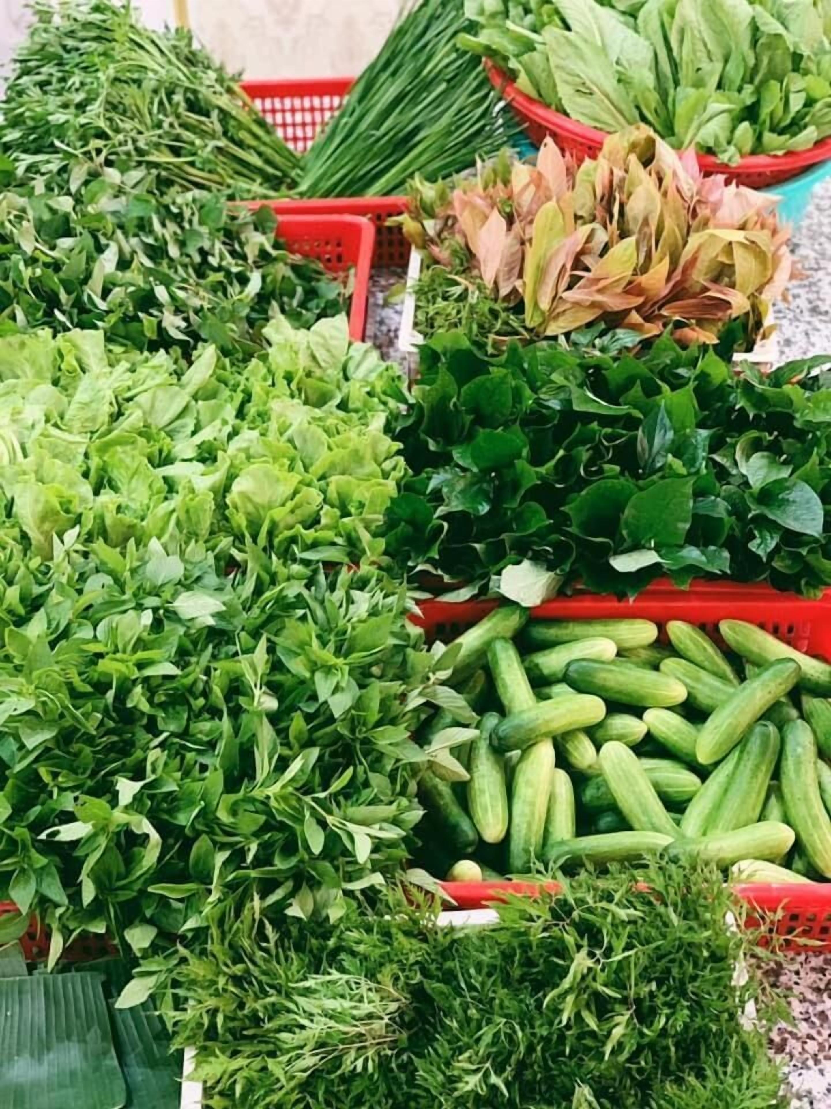 Verschiedene frische Gemüse in roten Körben auf einem Markt.