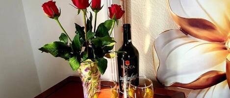 Una mesa con un jarrón de rosas rojas, una botella de vino y dos copas de vino.