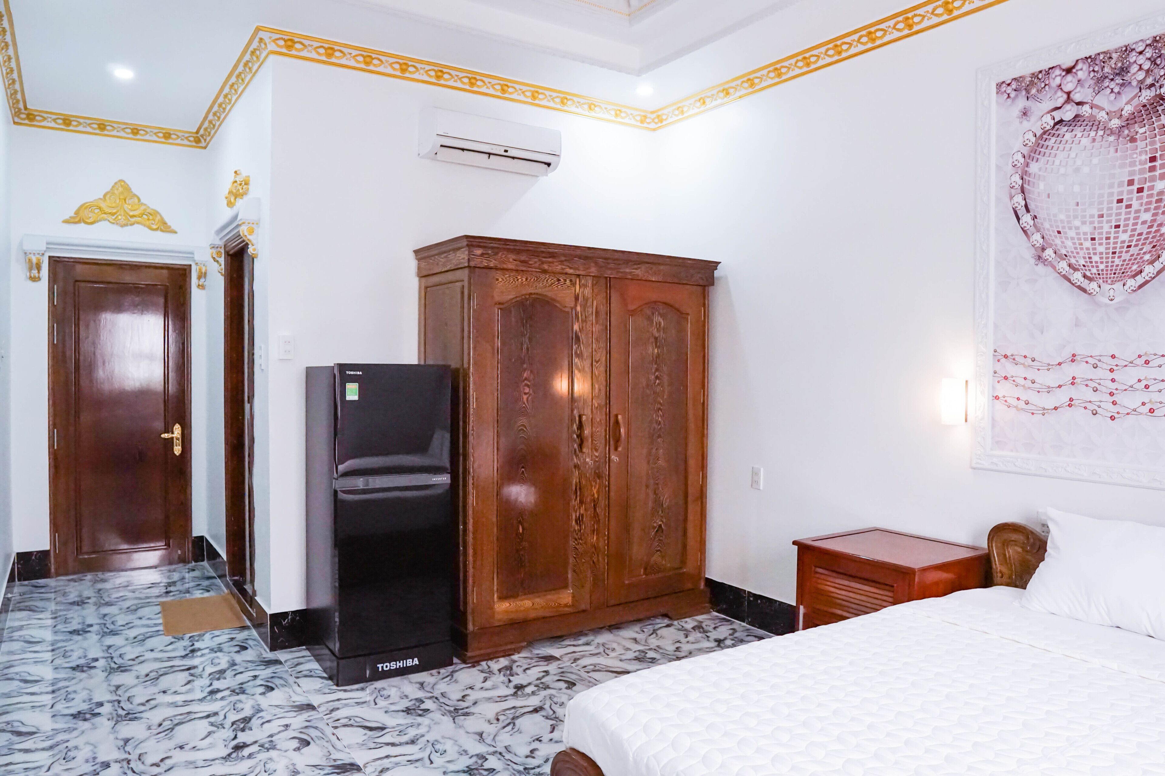 Hotellihuone, jossa on sänky, vaatekaappi ja jääkaappi.