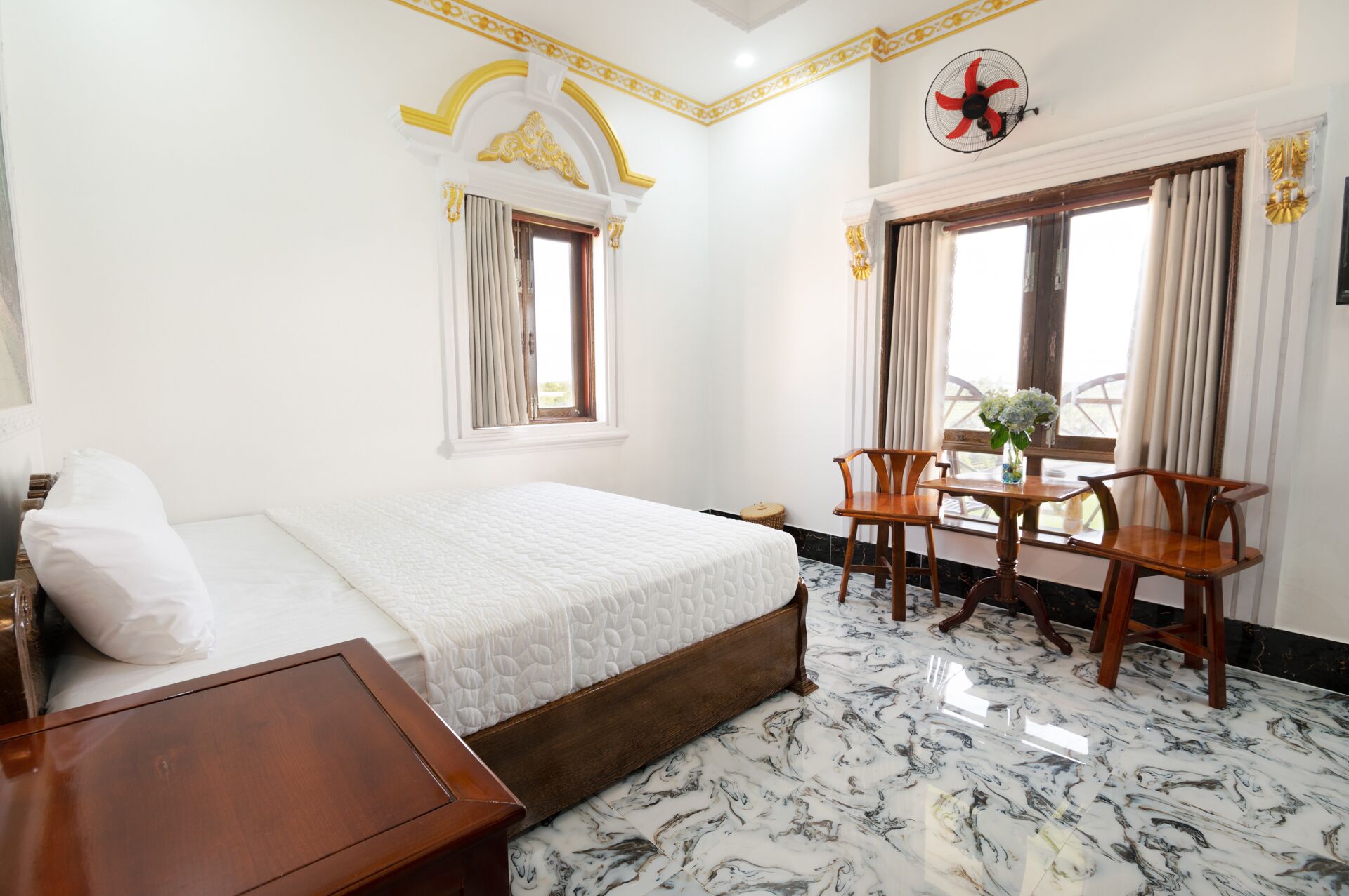 Ein Hotelzimmer mit Bett, einem kleinen Tisch mit Stühlen und einem Fenster mit Vorhängen.