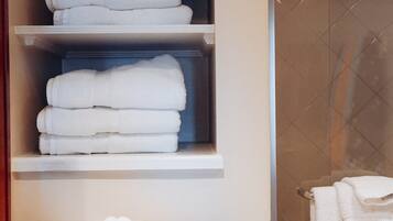A bathroom with a towel rack, a wicker basket, and a shelf with folded towels.