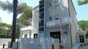Un edificio moderno con fachada blanca, varios balcones y un logotipo visible en la parte lateral.