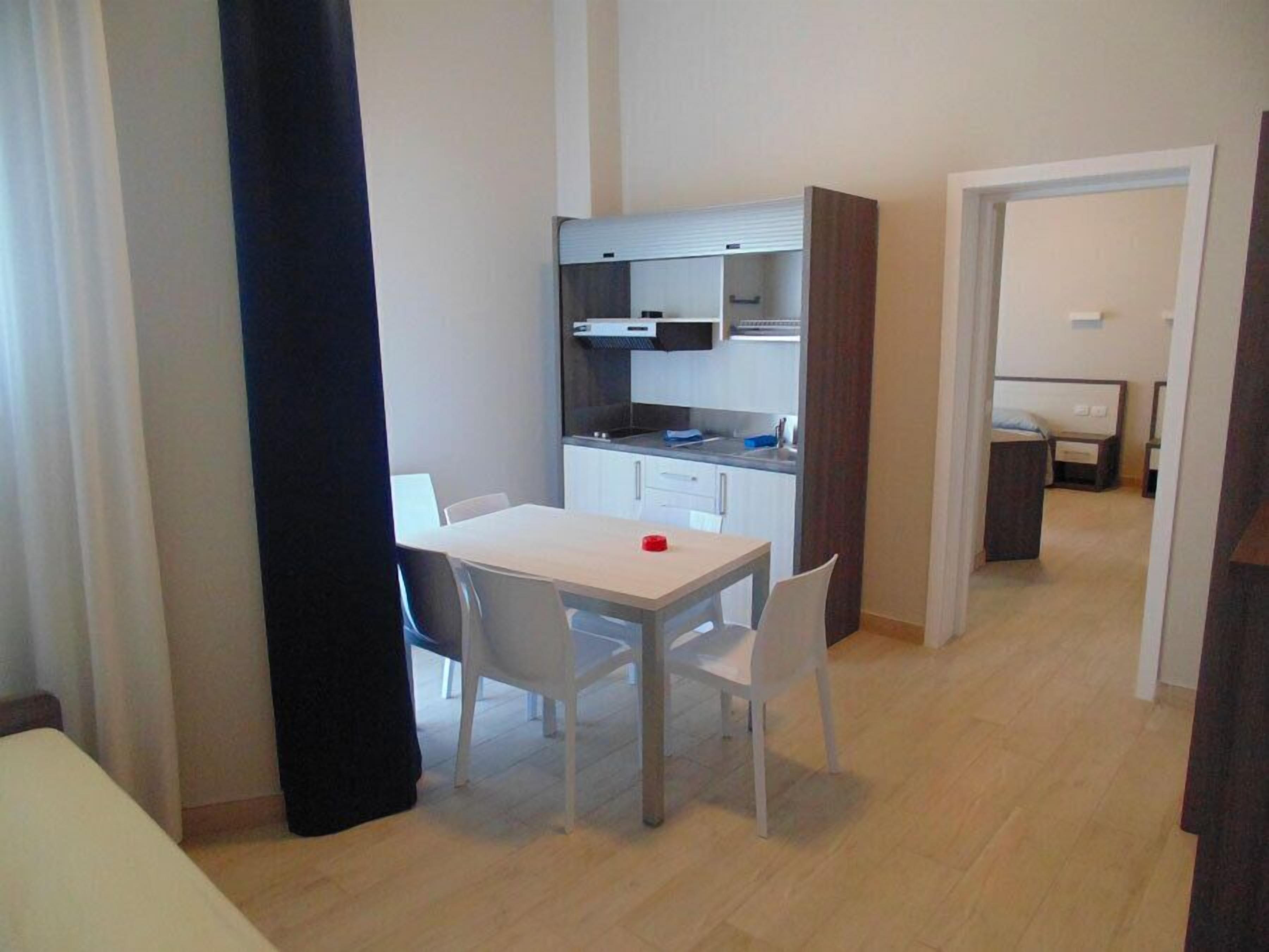 Une cuisine de taille réduite, avec des meubles blancs et un coin repas comprenant une table et des chaises.