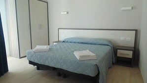 Un dormitorio con una cama, dos mesitas de noche, un armario y una mesita auxiliar.