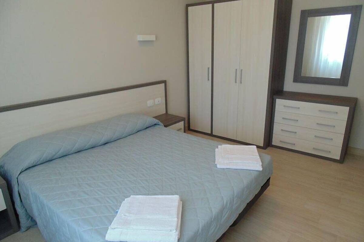 A bedroom with a bed, a wardrobe, a dresser, and a mirror.