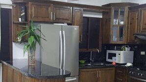 A kitchen with wooden cabinets, a refrigerator, a microwave, and a stove.