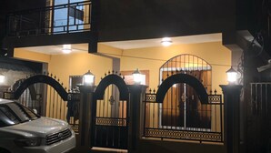 A two-story house with a gated entrance, a balcony, and a parked car.